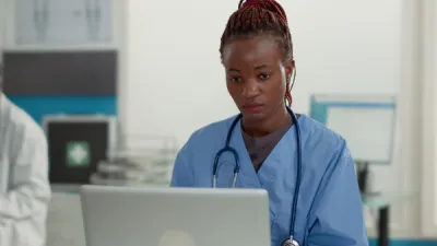 Female nurse in medical setting looking at laptop